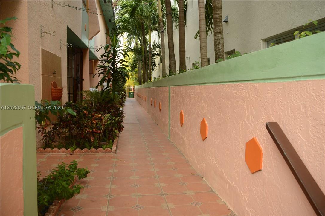 A narrow outdoor walkway with tiled flooring runs between a peach wall and building — 937 Michigan Ave # 3, Miami Beach FL 33139, MIAMI BEACH, FL