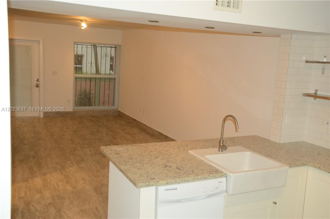 A kitchen island with a farmhouse sink faces an open living area with tiled floors — 937 Michigan Ave # 3, Miami Beach FL 33139, MIAMI BEACH, FL