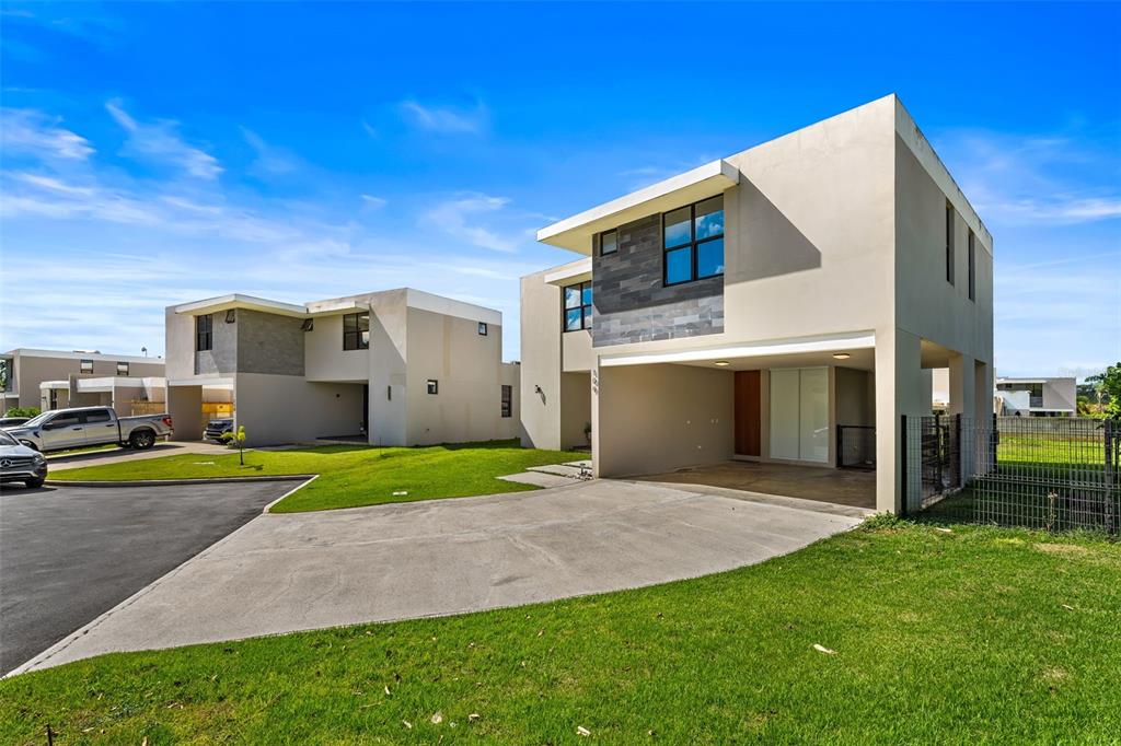 Two modern two-story houses with flat roofs, concrete driveways, and green lawns under a blue sky — 109 CALLE DANUBIO, GURABO, PR