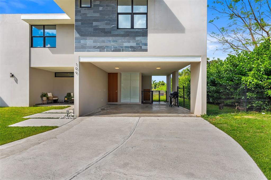A modern two-story house features a concrete driveway, a covered carport, and a small patio — 109 CALLE DANUBIO, GURABO, PR