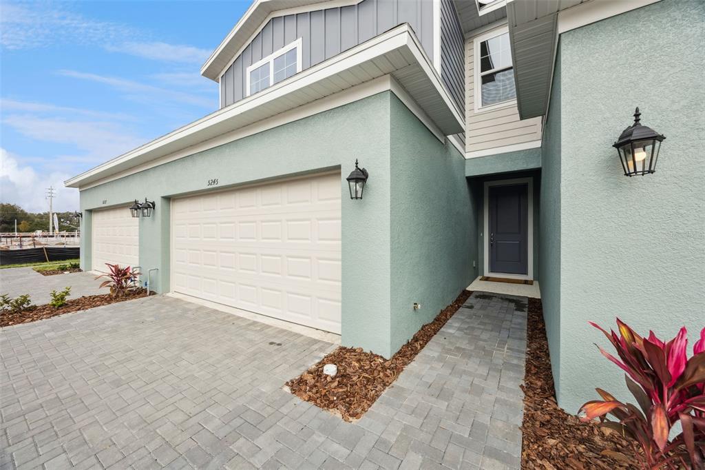 A light blue two-story house features a paved driveway, a garage, and a front entryway — 5212 LUISA COURT, ST CLOUD, FL