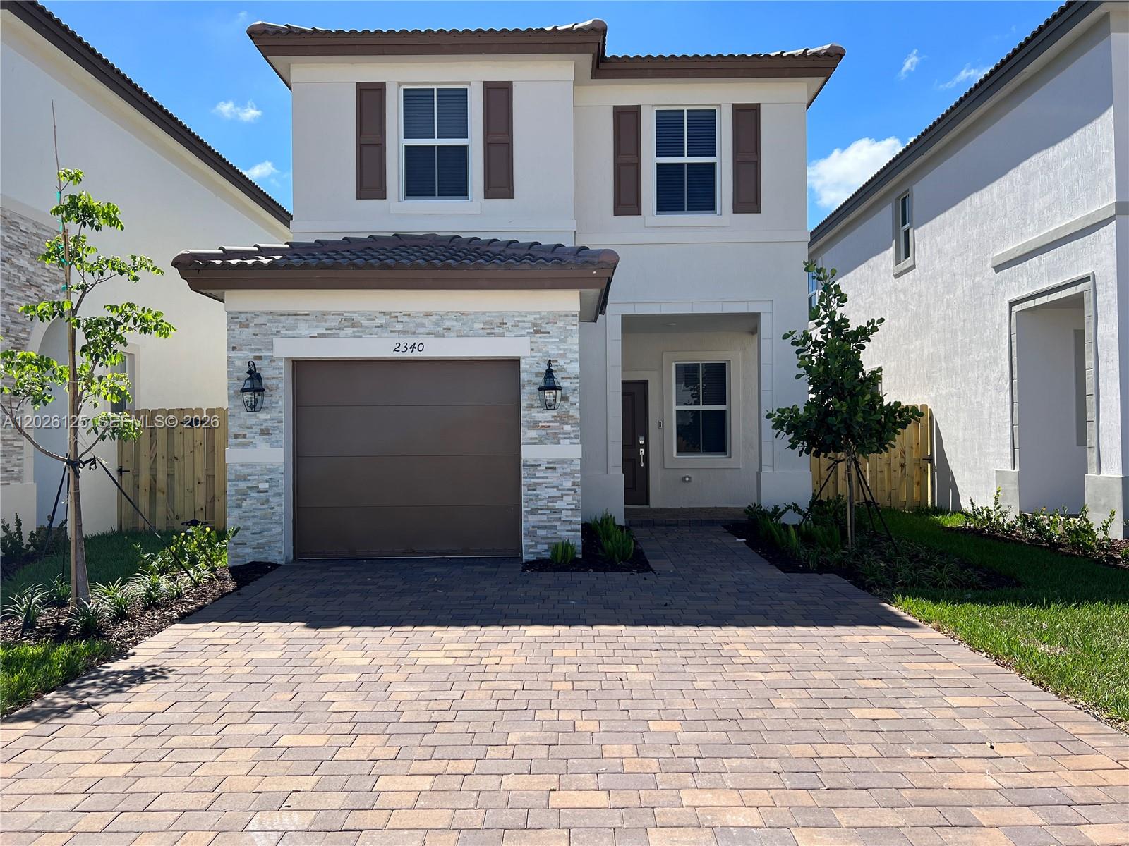 A two-story house with a stone-accented garage, brown shutters, and a paved driveway — 2340 NW 130 Terrace, Miami FL 33167, MIAMI, FL