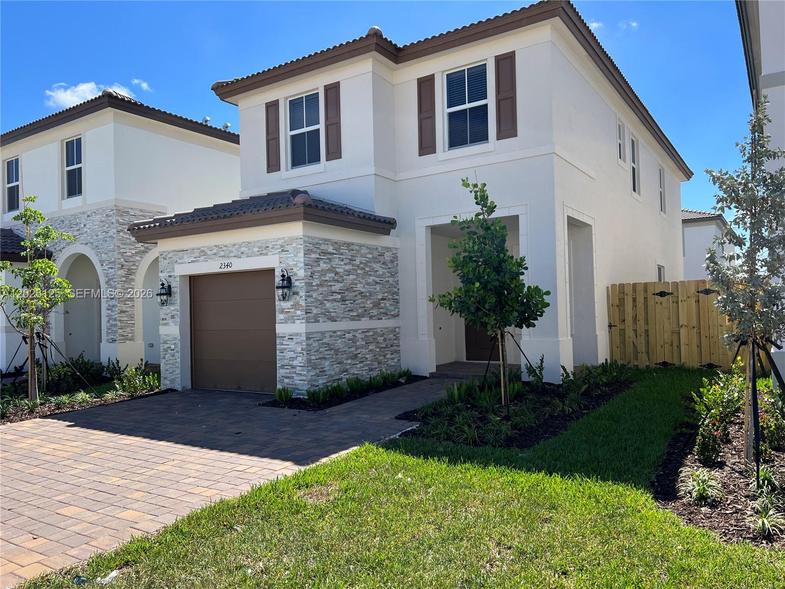 A two-story house with a stone-accented garage, brown shutters, and a paved driveway — 2340 NW 130 Terrace, Miami FL 33167, MIAMI, FL
