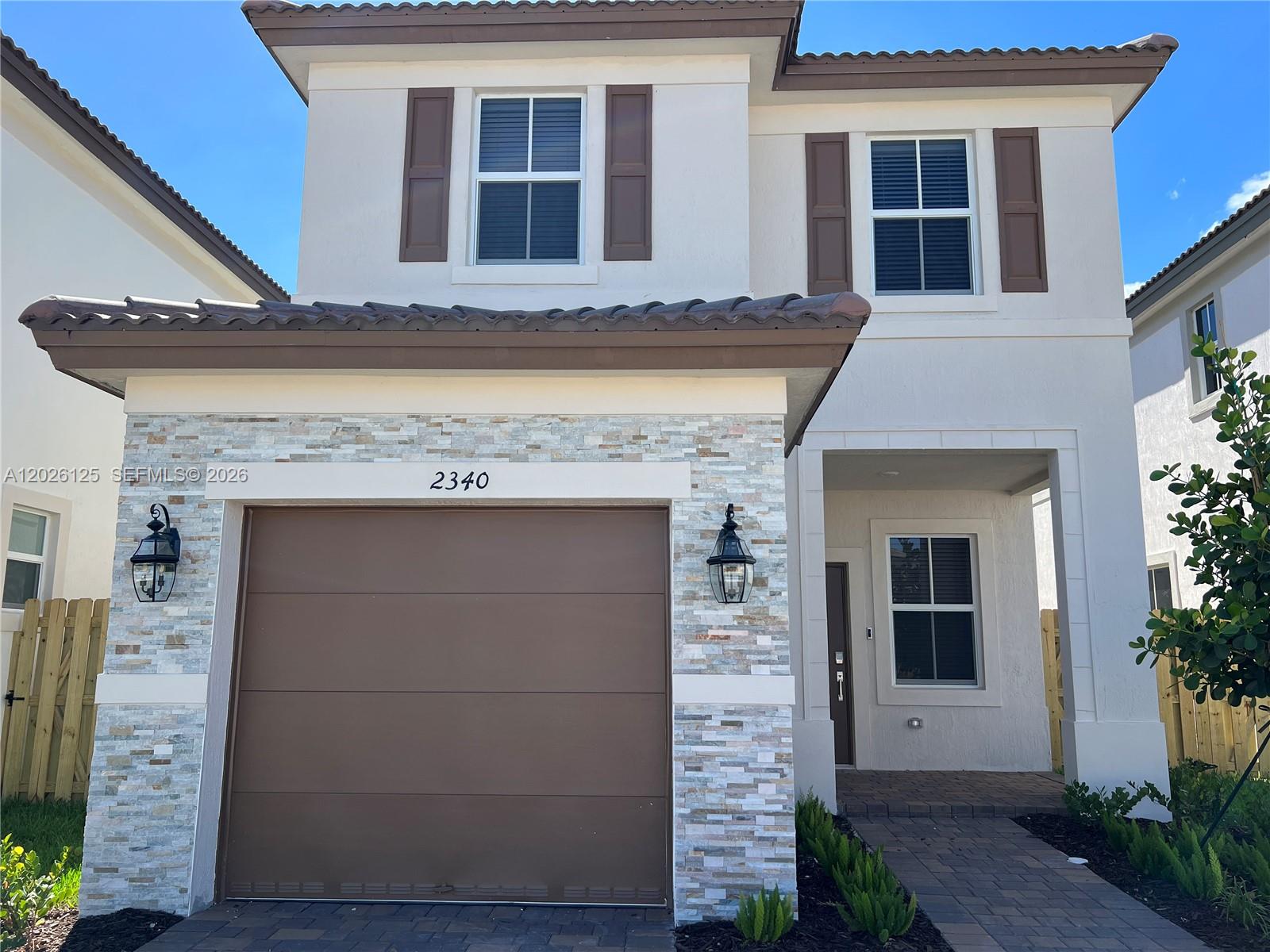 A two-story house features a stone-veneer garage, brown shutters, and a paved walkway — 2340 NW 130 Terrace, Miami FL 33167, MIAMI, FL