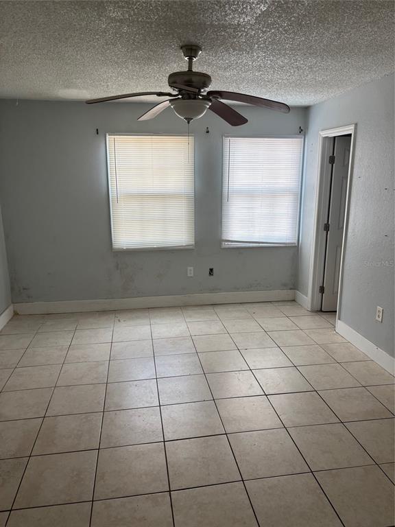 An empty room features light blue walls, a ceiling fan, and light-colored square floor tiles — 2779 L B MCLEOD ROAD UNIT A, ORLANDO, FL