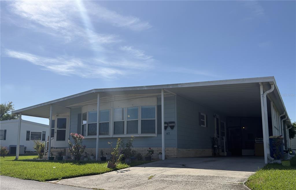 A light blue manufactured home with a covered carport and a concrete driveway — 2055 S FLORAL AVENUE UNIT 42, BARTOW, FL