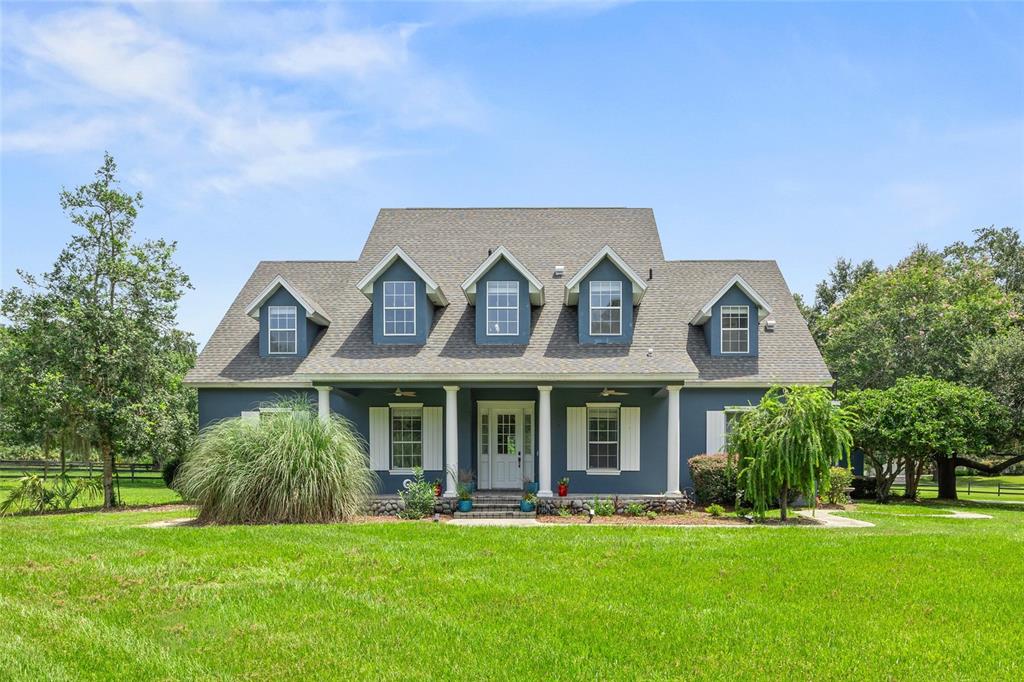 A blue two-story house with a front porch and five dormer windows on the roof — 25 SE 69TH PLACE, OCALA, FL