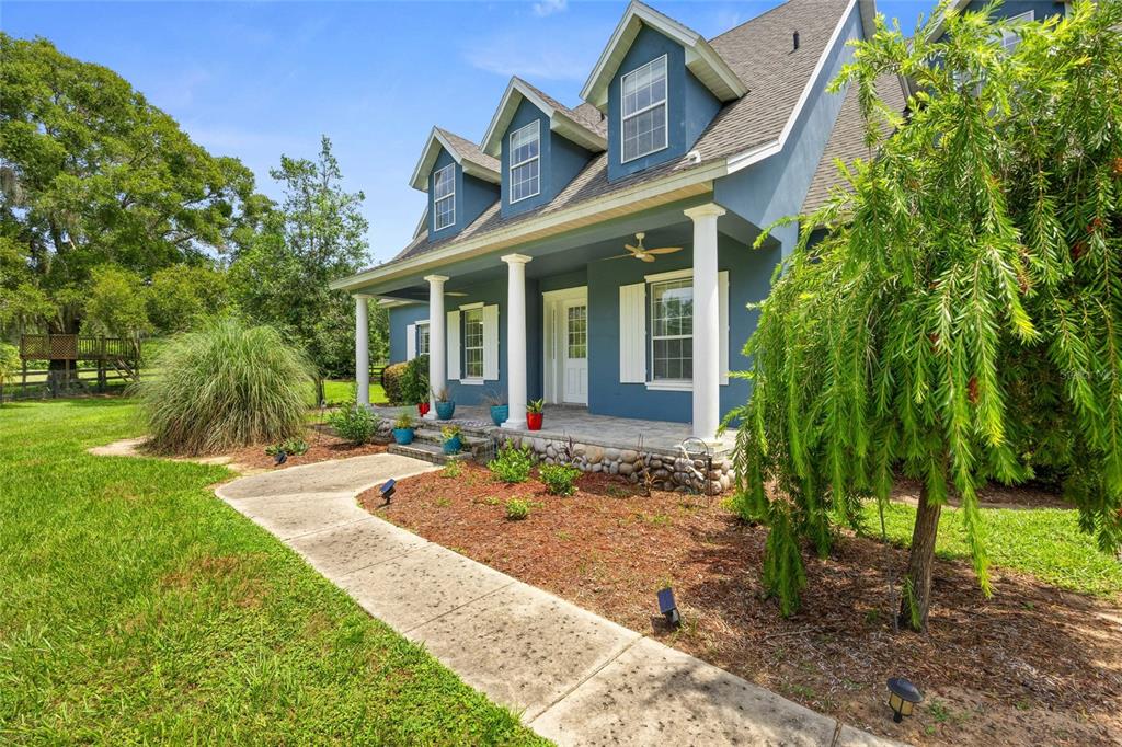 A blue house with a front porch, three dormer windows, and a concrete walkway — 25 SE 69TH PLACE, OCALA, FL