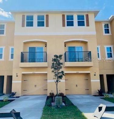 A three-story townhouse exterior with two garages, balconies, and light-colored stucco walls — 4916 GULF WATERS DRIVE, NEW PORT RICHEY, FL