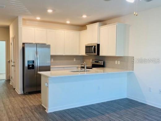 A modern kitchen features white cabinets, stainless steel appliances, and a breakfast bar island — 4916 GULF WATERS DRIVE, NEW PORT RICHEY, FL
