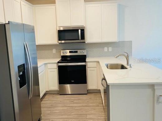 A kitchen with white cabinets, stainless steel appliances, and a quartz countertop island — 4916 GULF WATERS DRIVE, NEW PORT RICHEY, FL