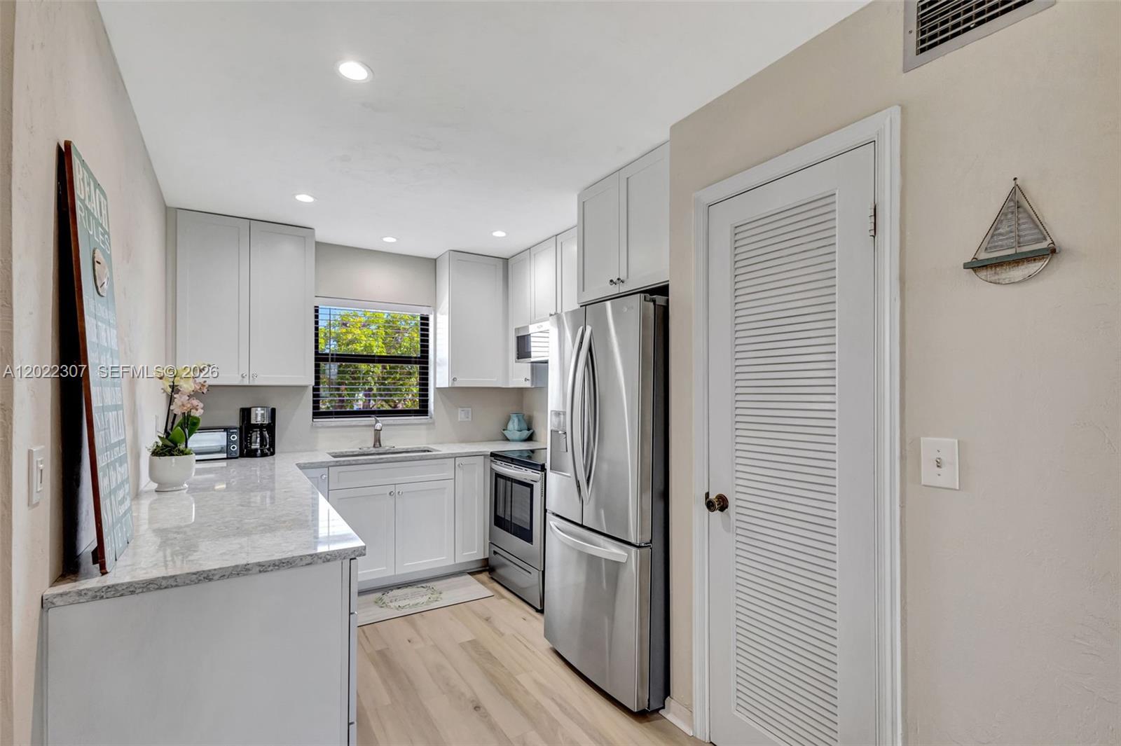 A kitchen features white cabinets, stainless steel appliances, and light-colored countertops — 755 Saturn St # G202, Jupiter FL 33477, JUPITER, FL