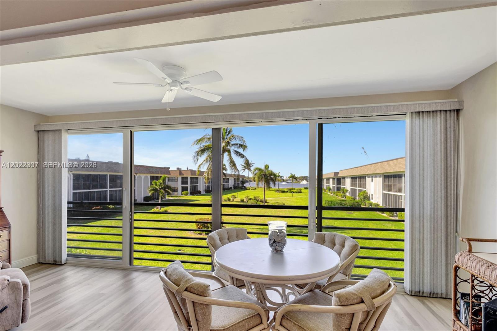 A dining area with a round table and chairs overlooks a grassy courtyard and water — 755 Saturn St # G202, Jupiter FL 33477, JUPITER, FL