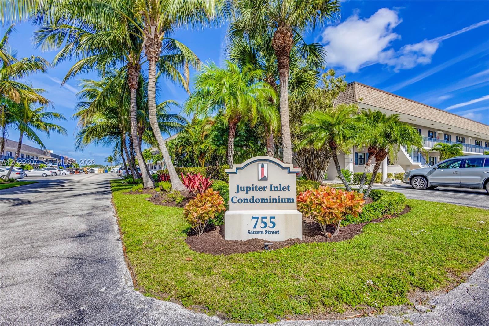 A sign for Jupiter Inlet Condominium stands in a landscaped area with palm trees — 755 Saturn St # G202, Jupiter FL 33477, JUPITER, FL