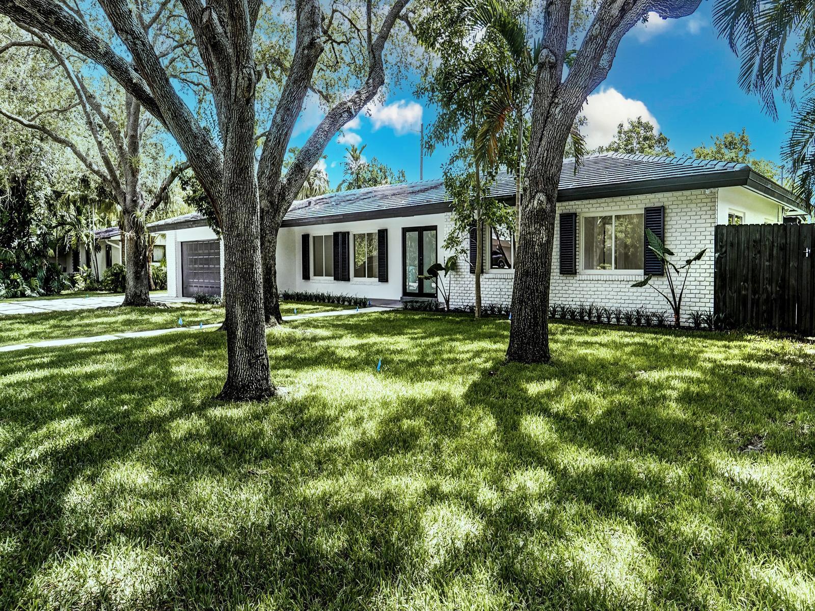 A single-story white brick house with a dark roof, shutters, and large trees in front — 12305 SW 73rd Avenue, Pinecrest FL 33156, PINECREST, FL