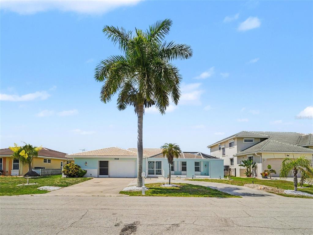 A light blue single-story house with a palm tree in the front yard — 548 BELVEDERE COURT, PUNTA GORDA, FL