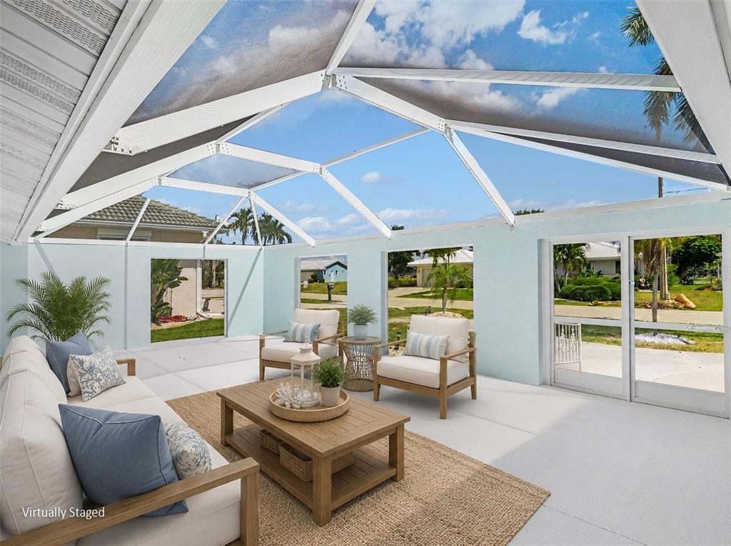 A sunroom with a screened roof, light blue walls, and patio furniture on a rug — 548 BELVEDERE COURT, PUNTA GORDA, FL