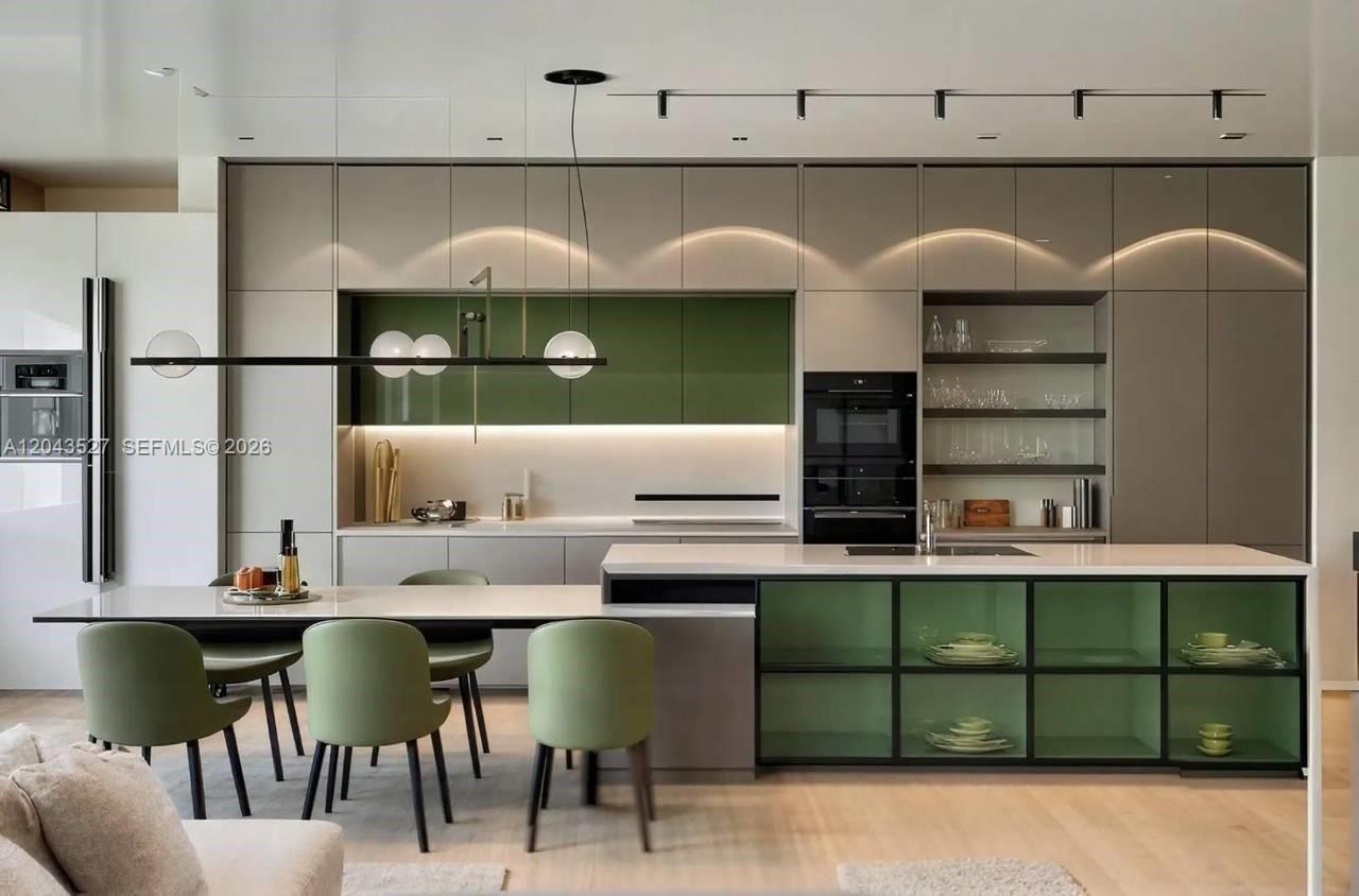A modern kitchen features sage green cabinetry, a central island, and integrated dining seating — 0 villa bekasi, FL