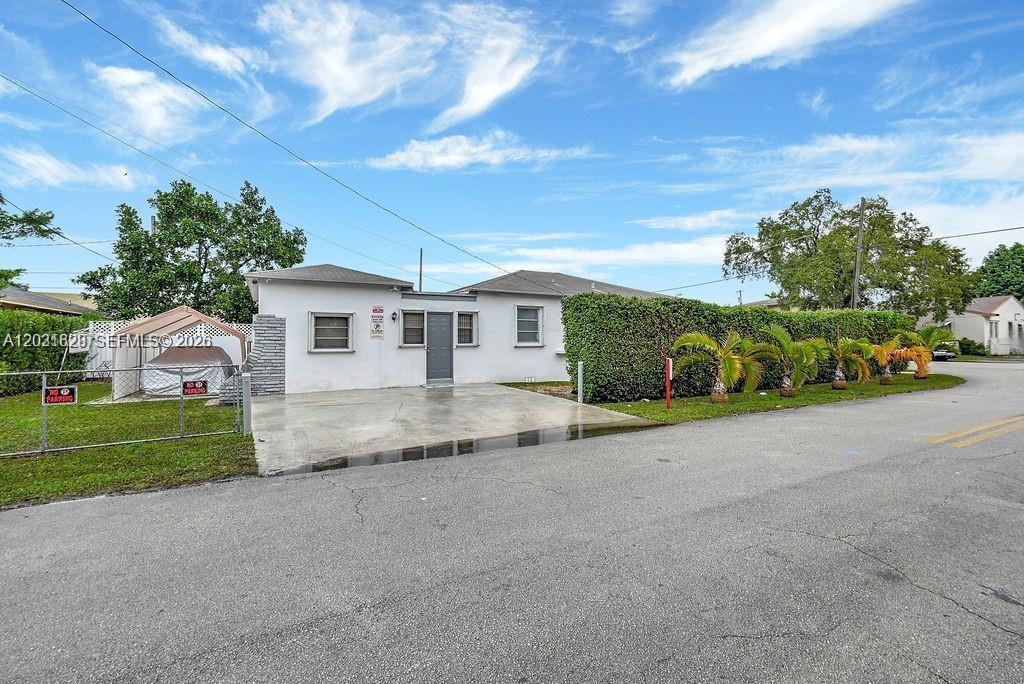 A single-story white house with a concrete driveway and a fenced yard — 600 NW 34th Ave, Miami FL 33125, MIAMI, FL