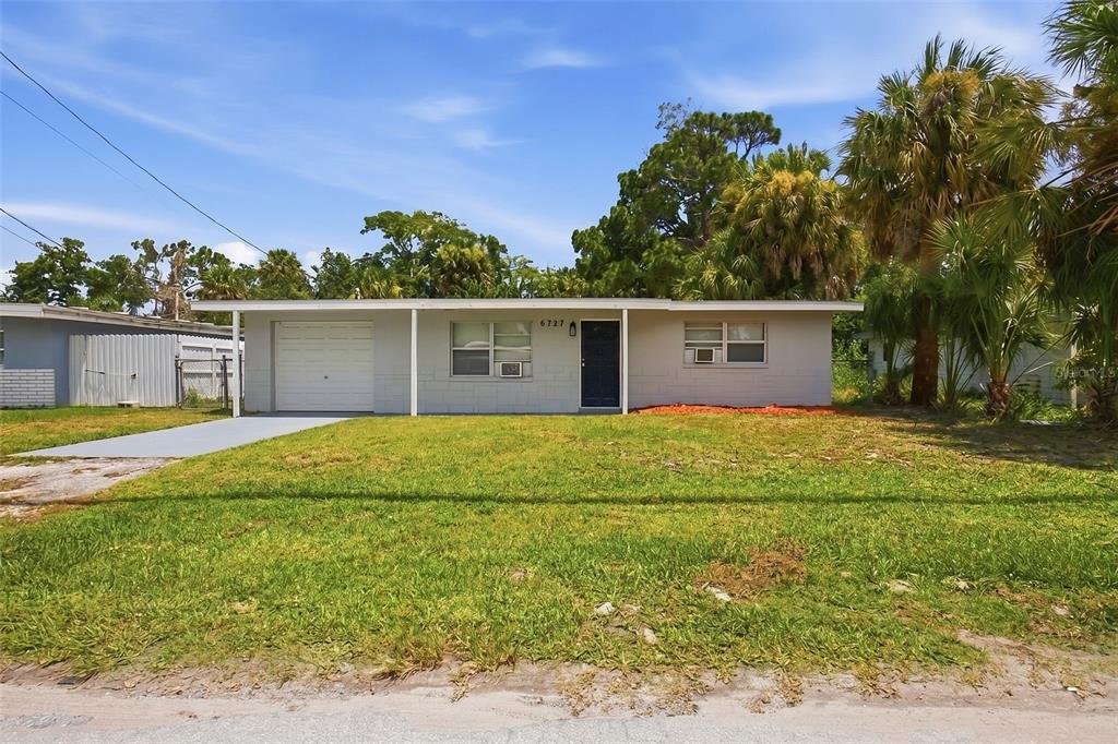 A single-story house with a white concrete block exterior, a garage, and a front lawn — 6727 SANDRA DRIVE, PORT RICHEY, FL