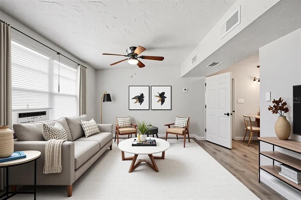 A living room features a gray sofa, two wooden chairs, a coffee table, and wood flooring — 6727 SANDRA DRIVE, PORT RICHEY, FL
