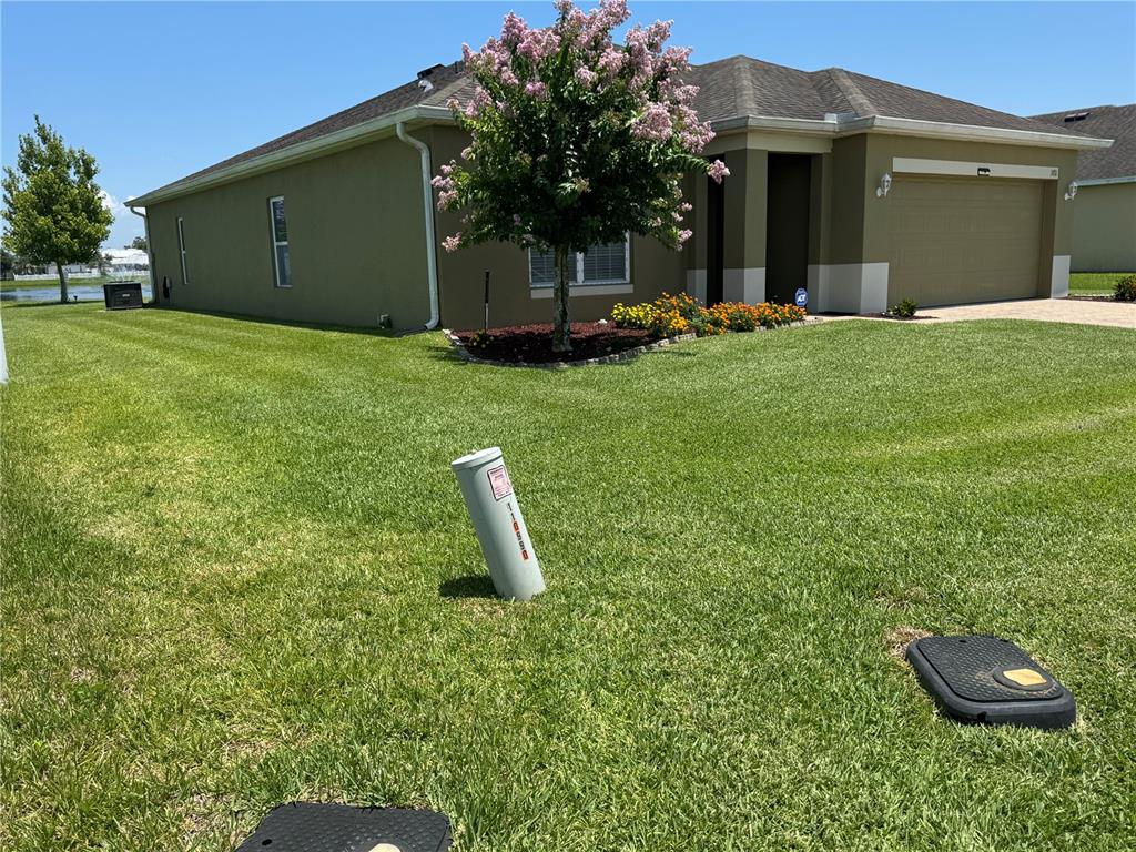 A tan house with a two-car garage and a landscaped front yard with utility boxes — 3711 BRIARWOOD ESTATES CIRCLE, ST CLOUD, FL