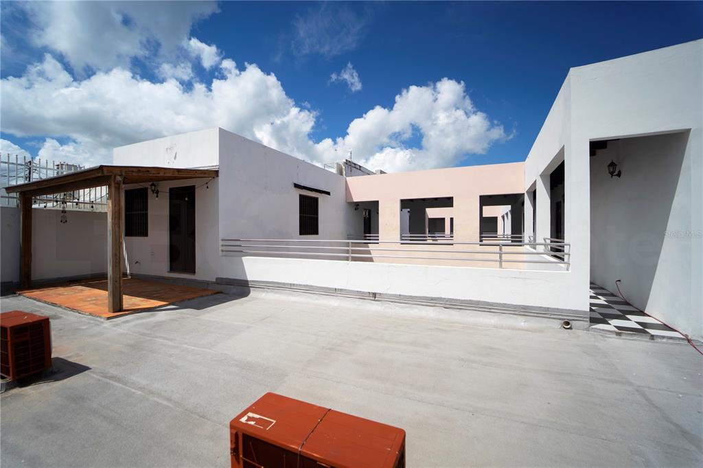 A spacious rooftop terrace features a wooden pergola, white exterior walls, and a metal railing — 153 SAN JUSTO, SAN JUAN, PR