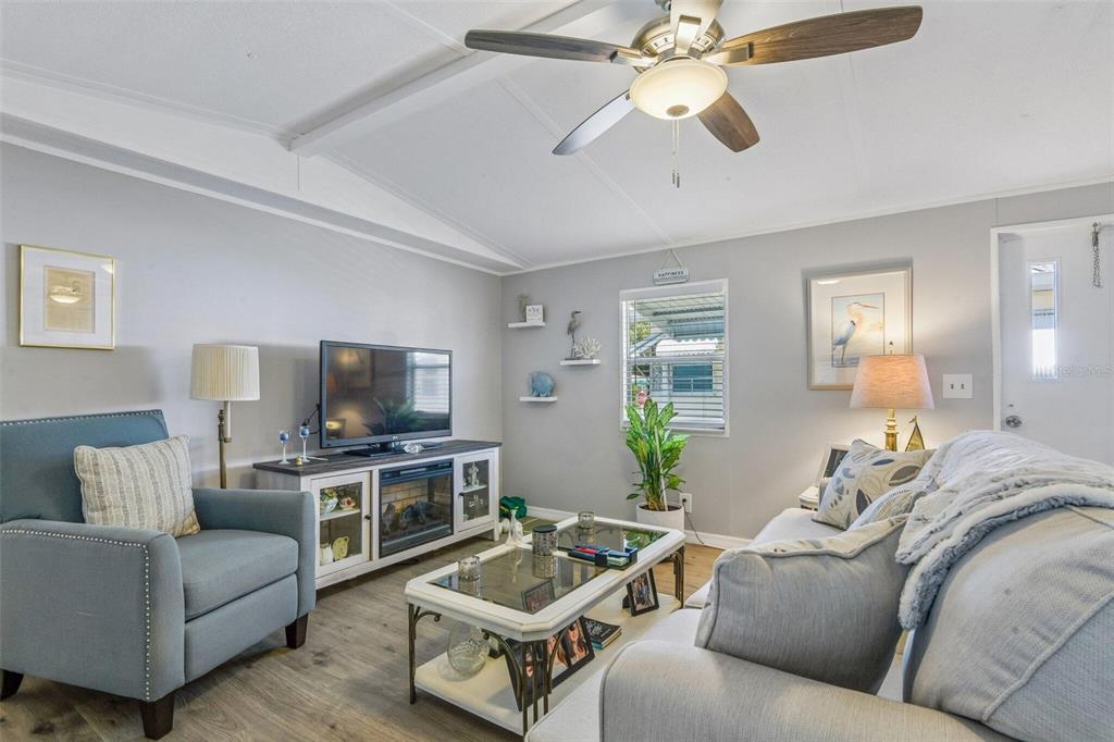 A living room features light gray walls, wood-look flooring, a ceiling fan, and neutral furniture — 3204 POND HOLLOW STREET, WESLEY CHAPEL, FL
