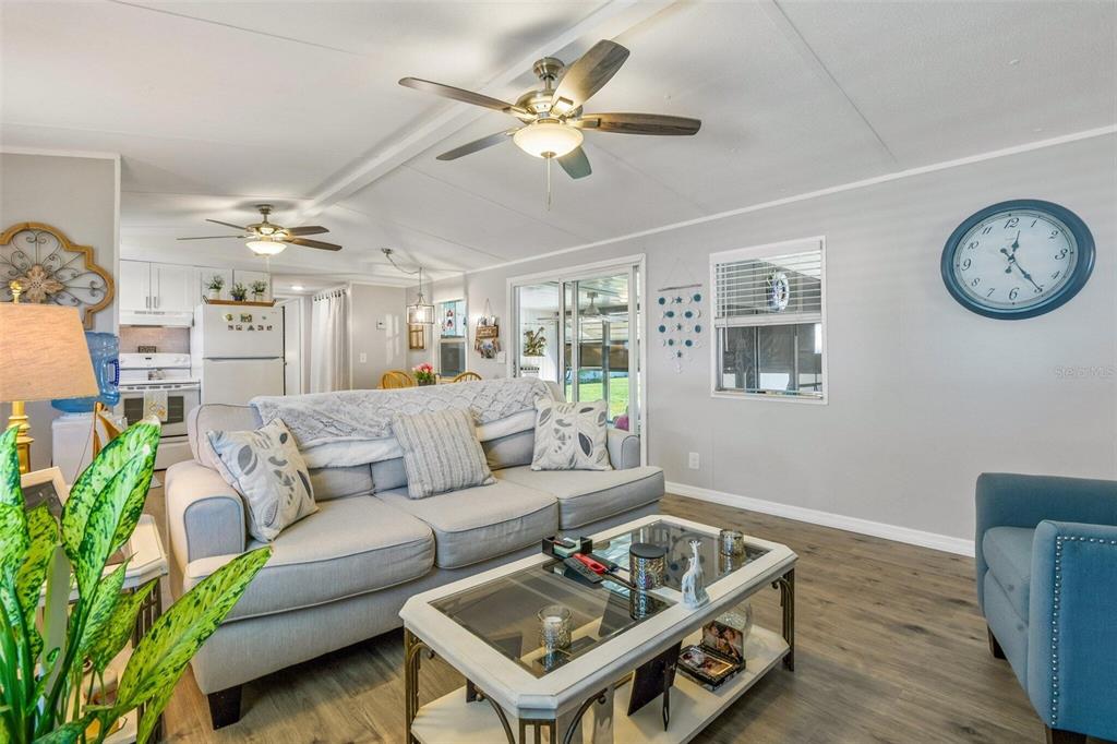A living room with a gray sofa, glass-top coffee table, ceiling fan, and blue wall clock — 3204 POND HOLLOW STREET, WESLEY CHAPEL, FL
