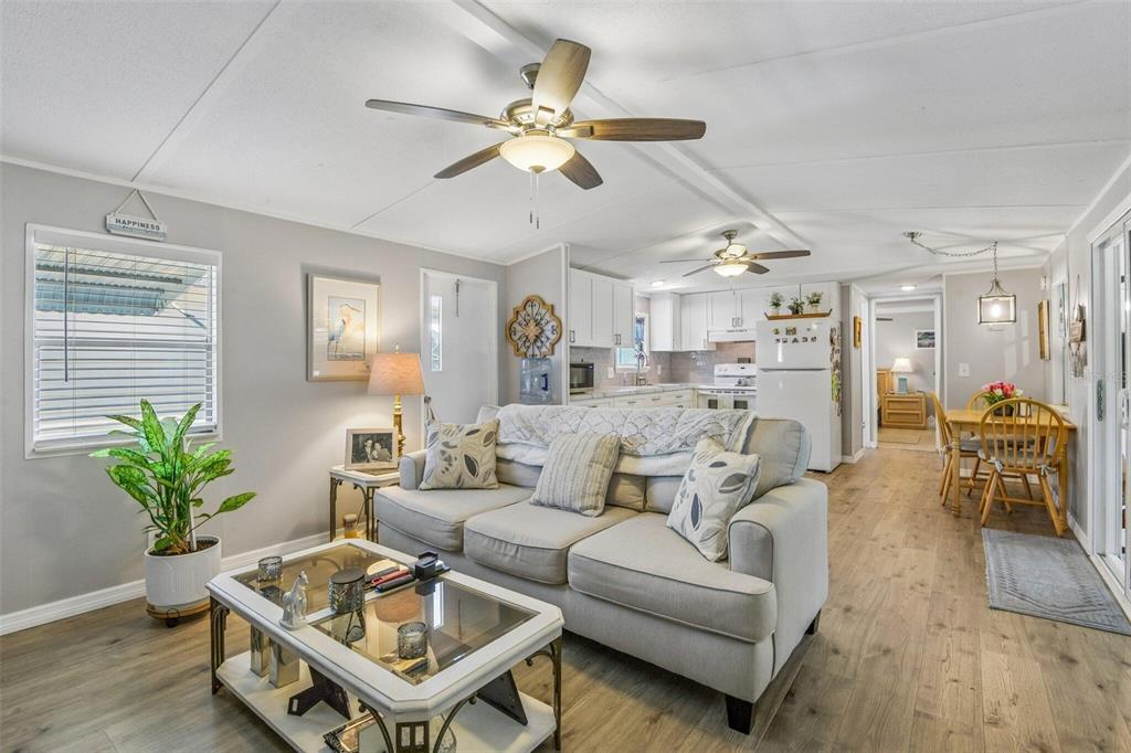 A living room with light wood floors, a sofa, a coffee table, and an open kitchen — 3204 POND HOLLOW STREET, WESLEY CHAPEL, FL
