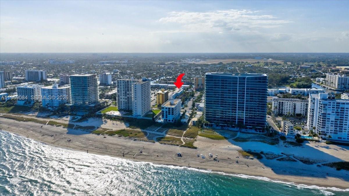 An aerial view shows multiple high-rise residential buildings situated along a sandy beach — 3201 NE 8th St # 405, Pompano Beach FL 33062, POMPANO BEACH, FL