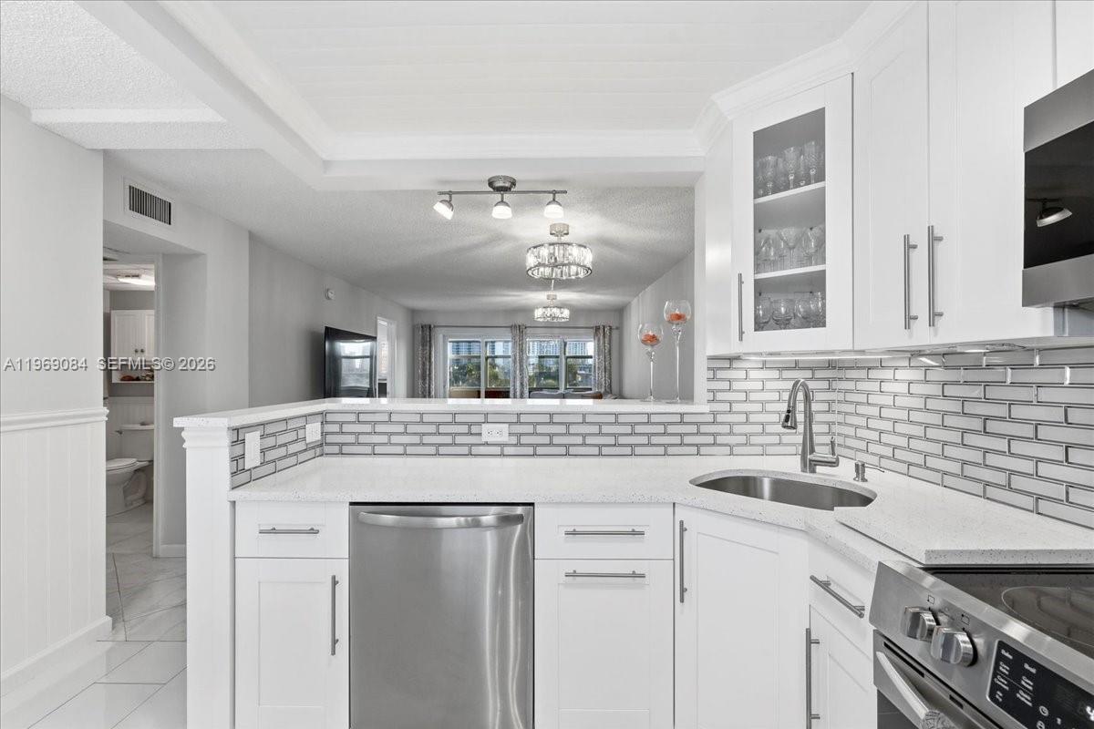 A modern kitchen features white cabinets, stainless steel appliances, and a subway tile backsplash — 3201 NE 8th St # 405, Pompano Beach FL 33062, POMPANO BEACH, FL