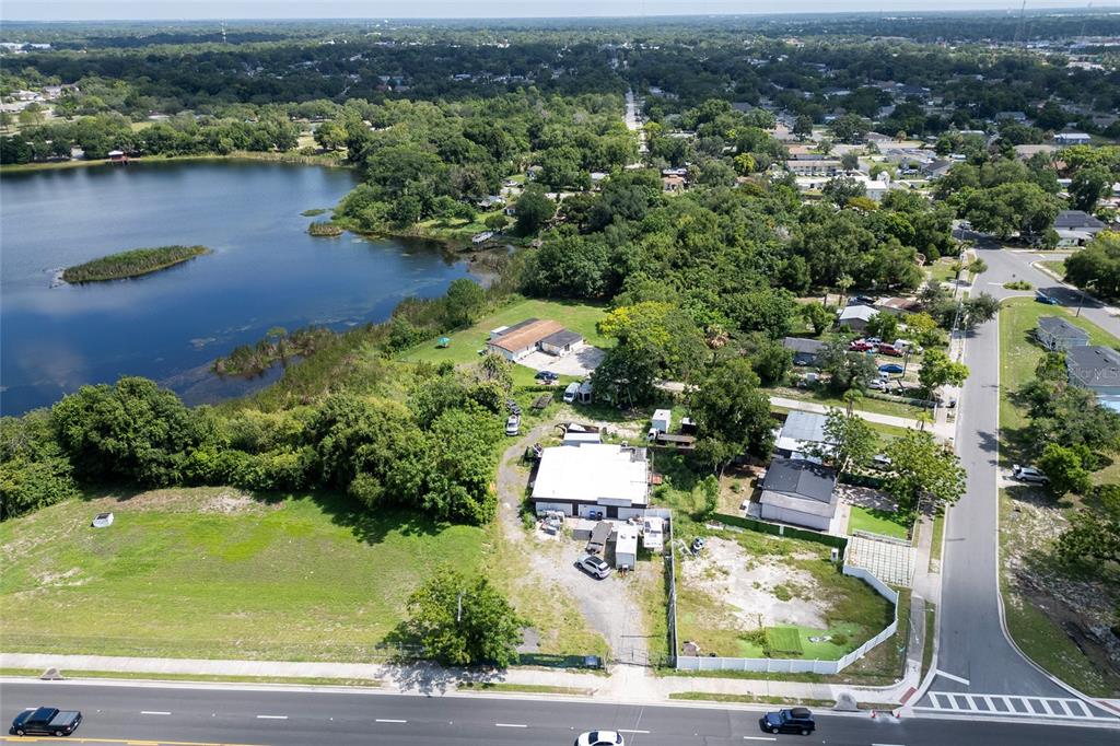 An aerial view shows a commercial property with a white building near a lake — 6011 OLD WINTER GARDEN ROAD, ORLANDO, FL