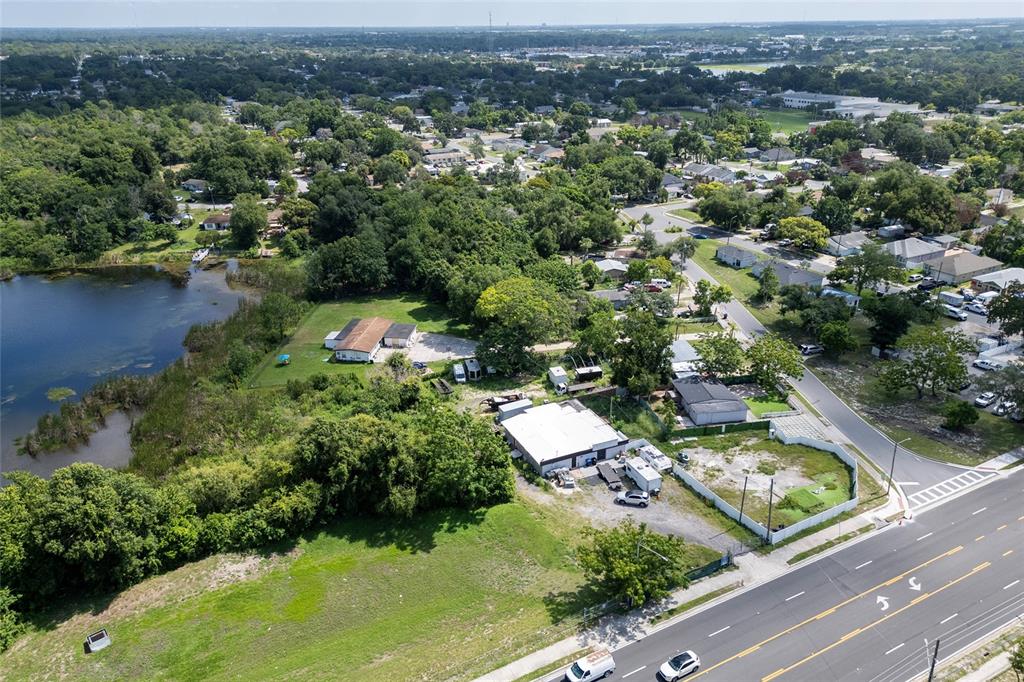 An aerial view shows a commercial property with two buildings situated near a lake — 6011 OLD WINTER GARDEN ROAD, ORLANDO, FL