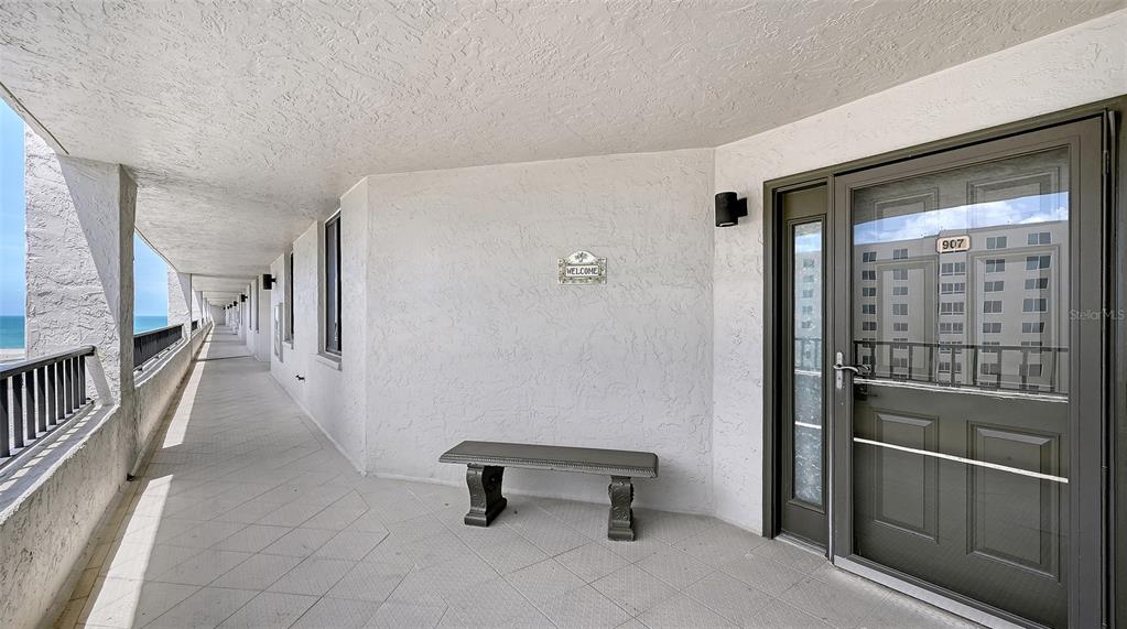 A long outdoor balcony with a bench and a door marked 907 overlooks the ocean — 5880 MIDNIGHT PASS ROAD UNIT 907, SARASOTA, FL