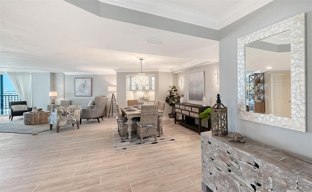 An open-concept living and dining area features light wood-look tile flooring and neutral decor — 5880 MIDNIGHT PASS ROAD UNIT 907, SARASOTA, FL