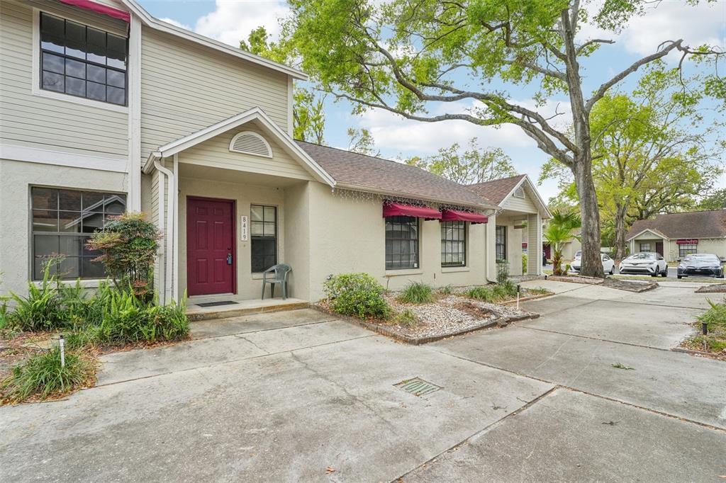 A two-story tan townhouse with a red front door and a concrete driveway — 8419 LAURELON PLACE, TEMPLE TERRACE, FL
