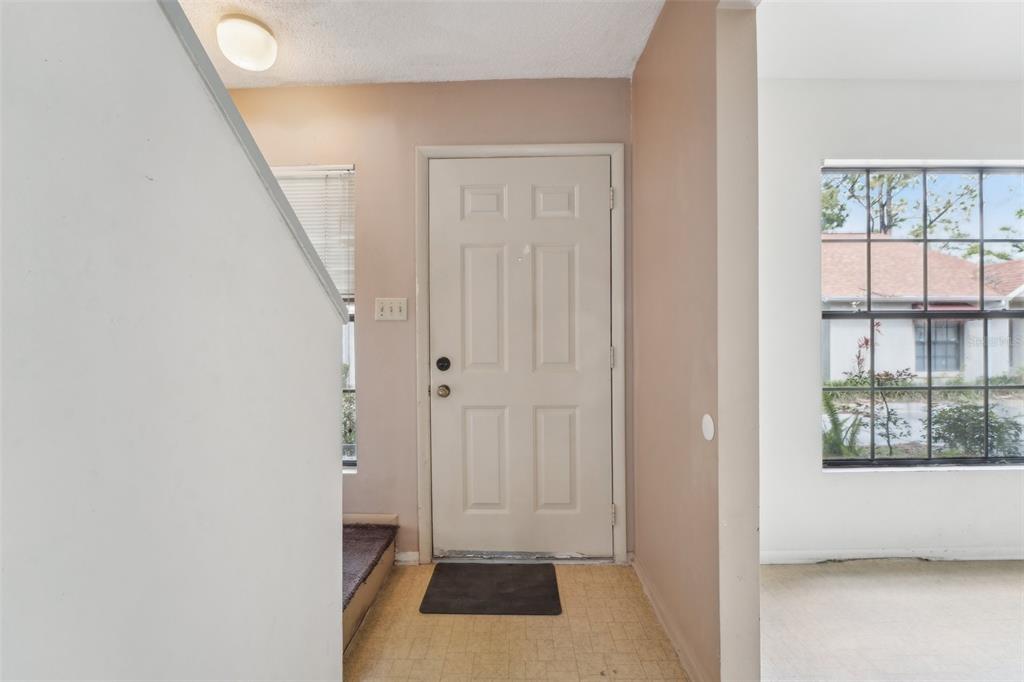 An entryway features a white front door, beige walls, and a tiled floor — 8419 LAURELON PLACE, TEMPLE TERRACE, FL