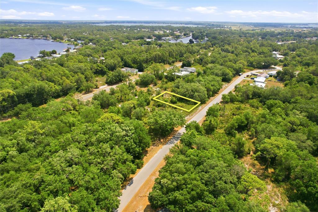 An aerial view shows a rectangular vacant lot outlined in yellow amidst a wooded area — 3392 GOSSAMER AVENUE, LAKE PLACID, FL