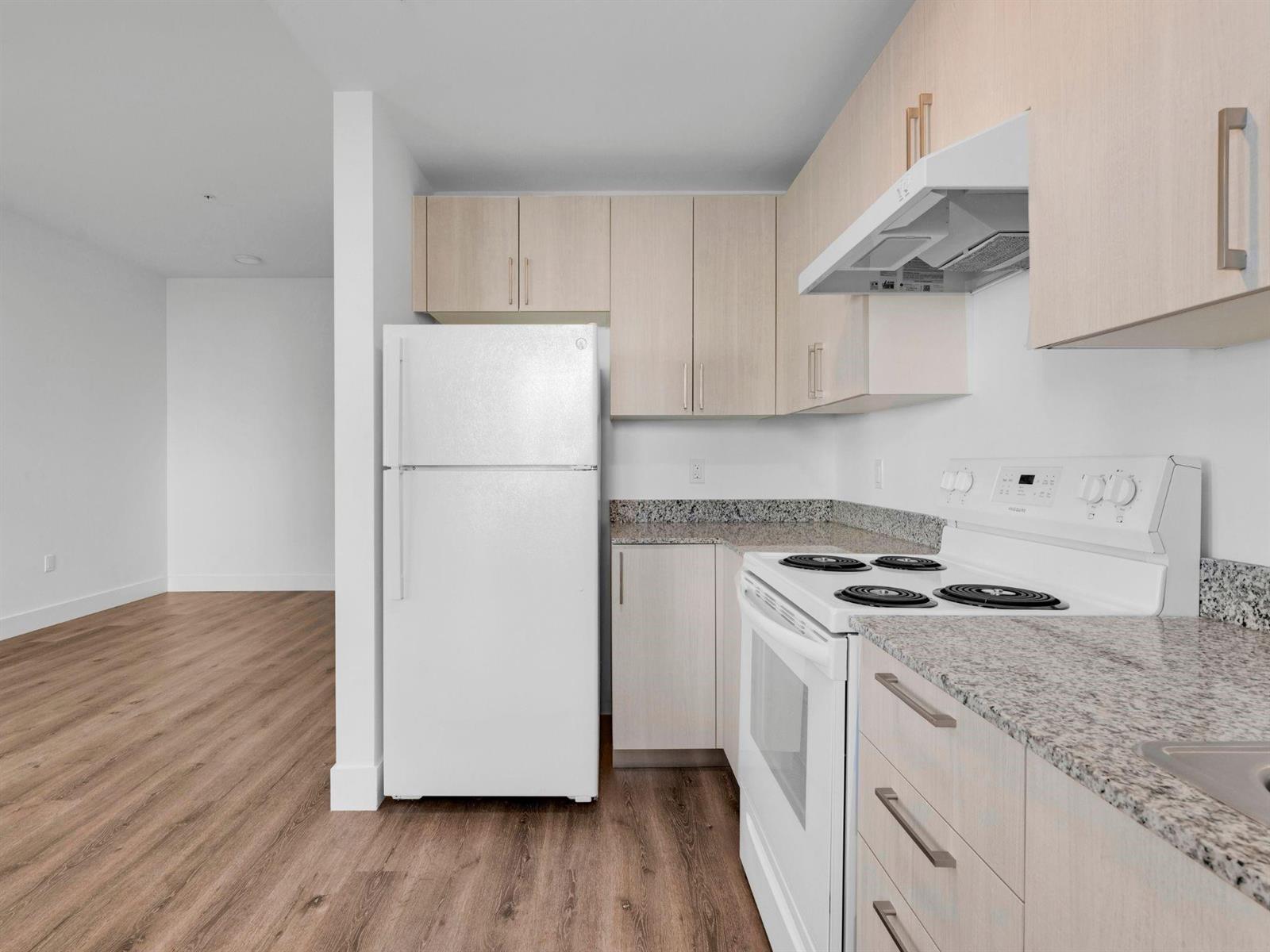 A kitchen with light wood cabinets, white appliances, and granite countertops next to a living area — 2130 NW 37th Street, Miami FL 33142, MIAMI, FL