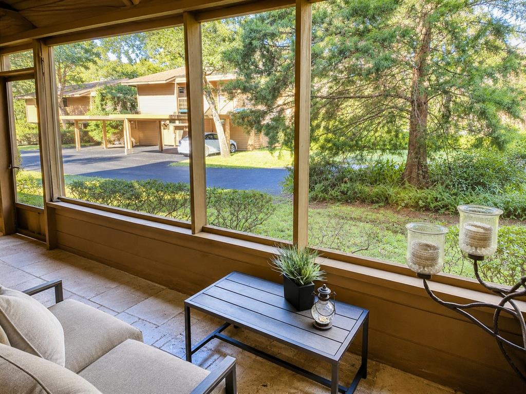 A screened-in porch with tile flooring overlooks a parking area and trees — 1503 LENNOX ROAD E UNIT 1503, PALM HARBOR, FL