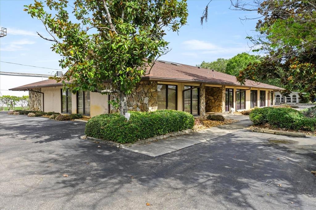 A single-story commercial building features stone accents, a brown shingled roof, and surrounding landscaping — 9009 PARK BOULEVARD UNIT Suite B, SEMINOLE, FL
