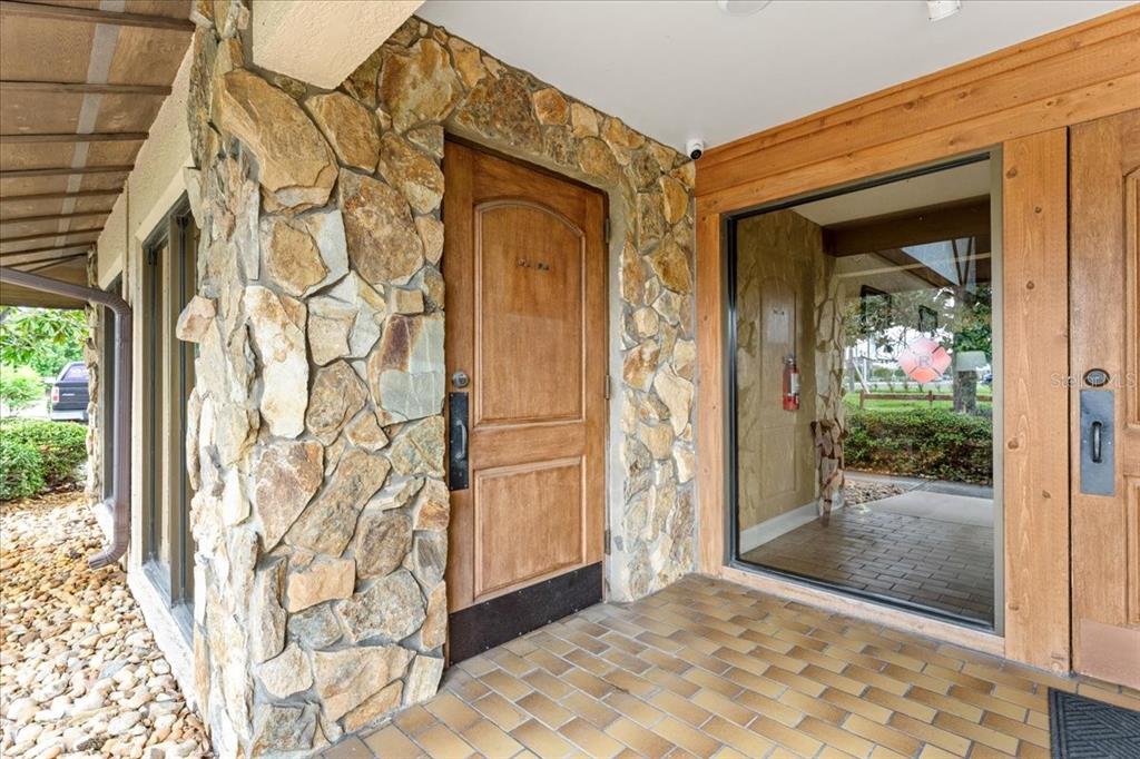 A stone-clad building entrance features a wooden door and a large glass window — 9009 PARK BOULEVARD UNIT Suite B, SEMINOLE, FL