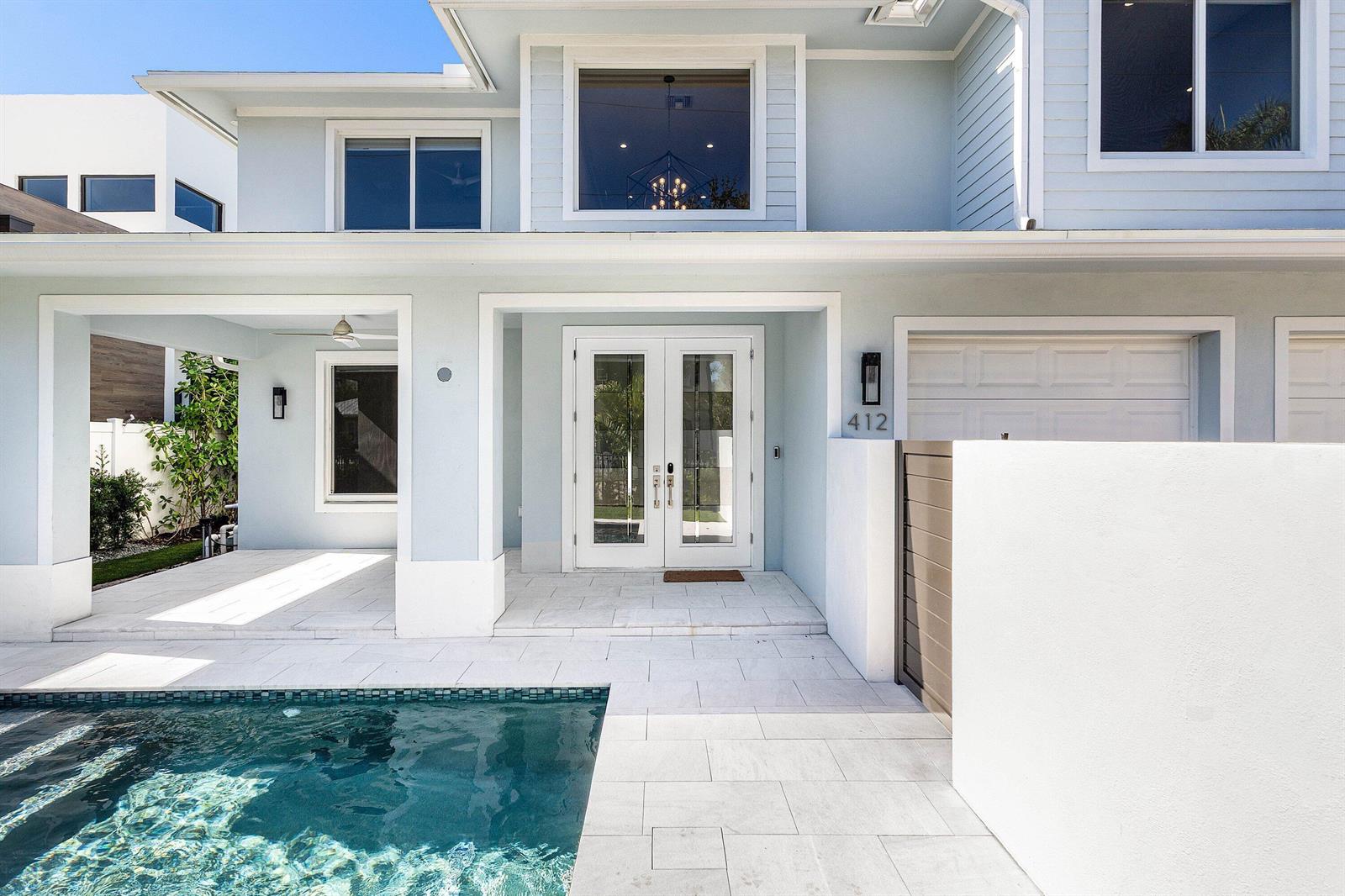A light blue two-story house features a front patio with a pool and double doors — 412 SE 4th Avenue, Delray Beach FL 33483, DELRAY BEACH, FL