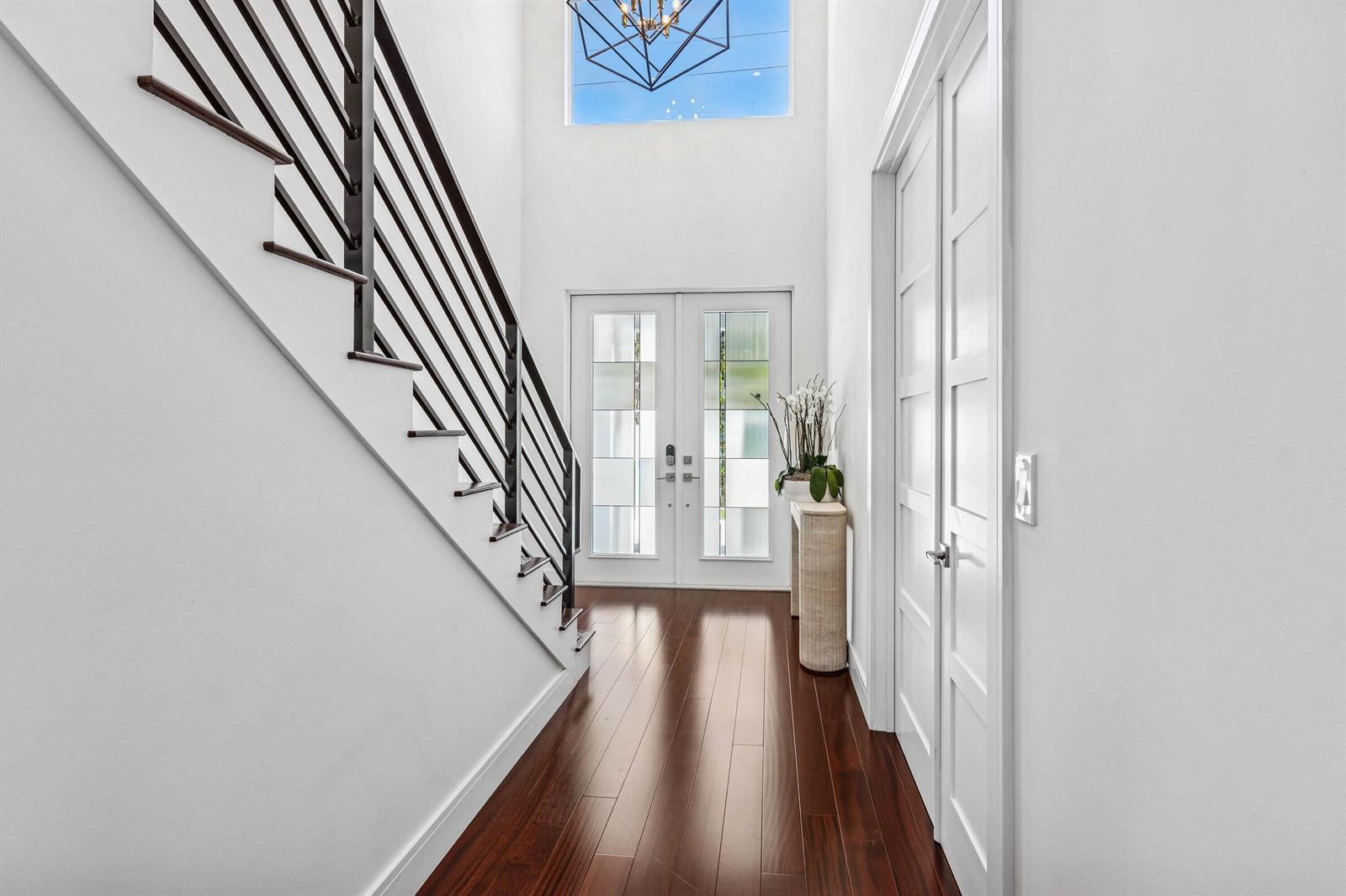 A bright entryway features a dark wood staircase, white walls, and double front doors — 412 SE 4th Avenue, Delray Beach FL 33483, DELRAY BEACH, FL