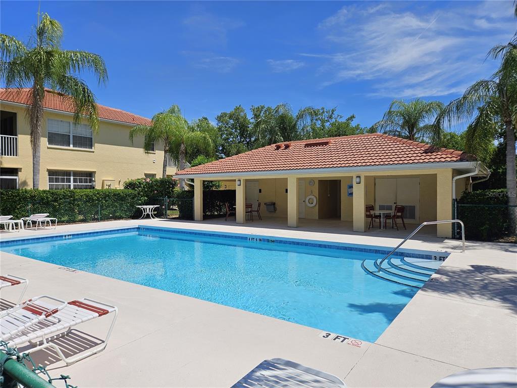 An outdoor swimming pool with a covered patio area and lounge chairs — 904 CASA DEL LAGO WAY UNIT 904, VENICE, FL