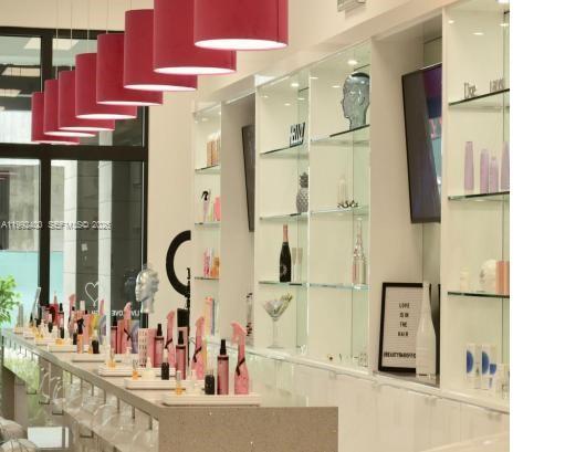 A bright salon interior features a long counter with product displays and pink pendant lights — 12700 SW 128th St, Miami FL 33186, MIAMI, FL