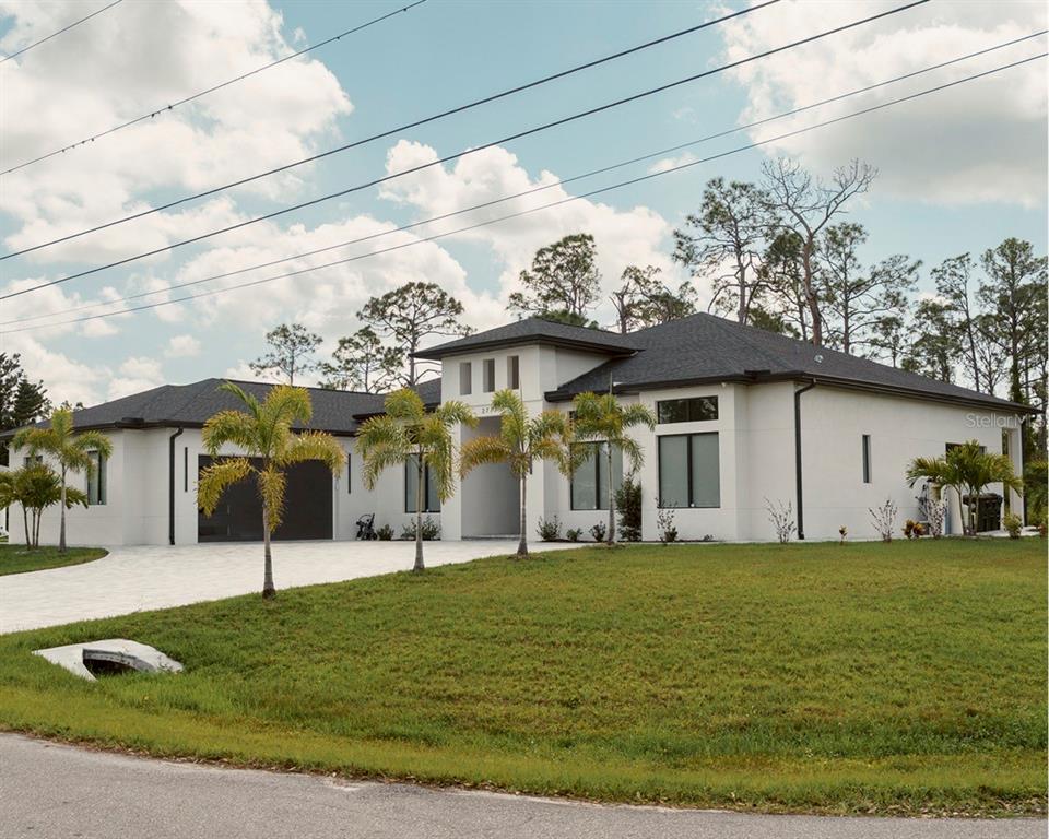 A modern white house exterior features a central entryway with double doors and a roof overhang — 2777 LUCAYA AVENUE, NORTH PORT, FL