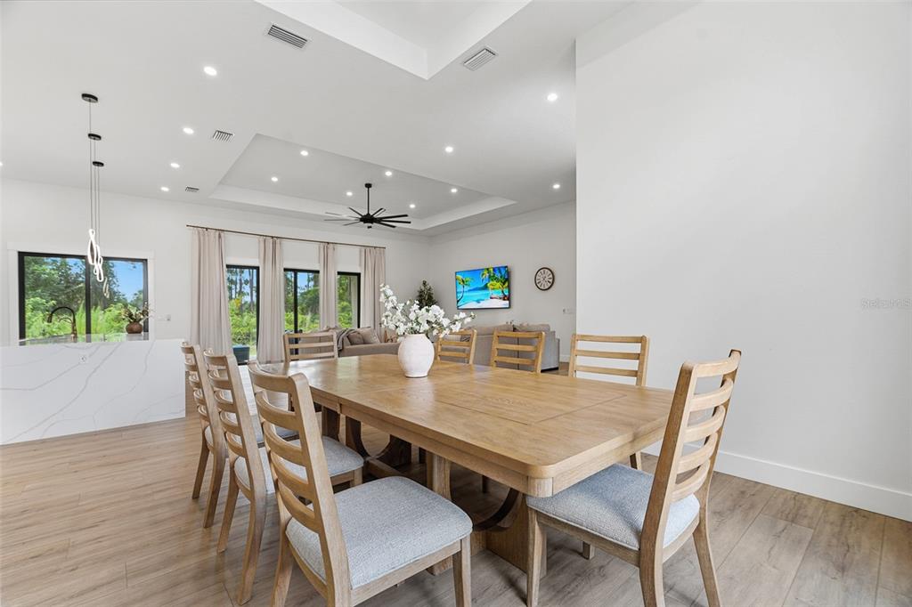 A dining area with a wooden table and chairs opens into a spacious living room — 2777 LUCAYA AVENUE, NORTH PORT, FL