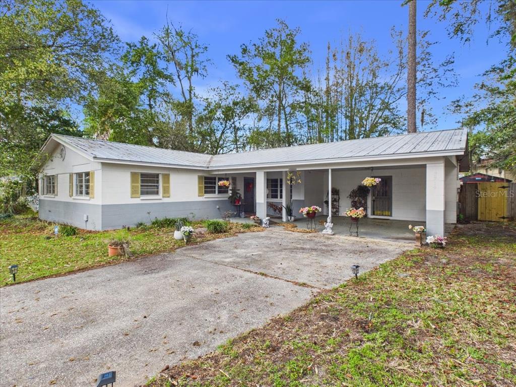 A single-story house with a metal roof, white and gray exterior, and a front carport — 3314 NW 45TH AVENUE, GAINESVILLE, FL